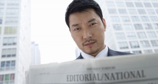 Asian man reading newspaper