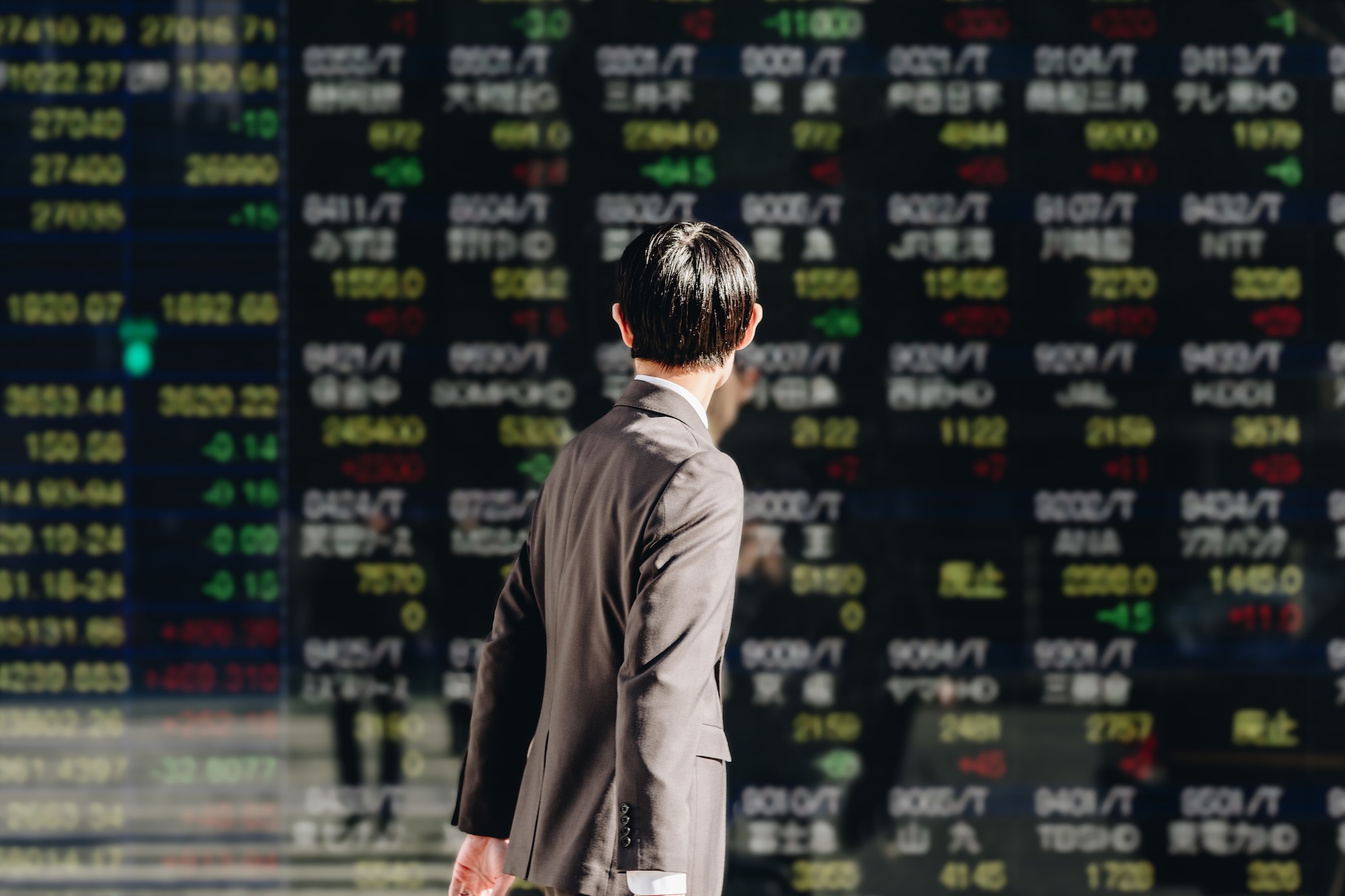 Young man looks at digital stock market display in Asia