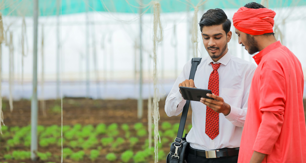 Young Indian agronomist and farmer discussing technological solutions
