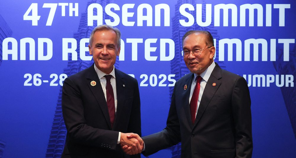 Prime Minister Mark Carney (L) shakes hands with Malaysia's Prime Minister Anwar Ibrahim