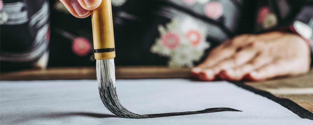 Closeup of someone painting with a calligraphy brush