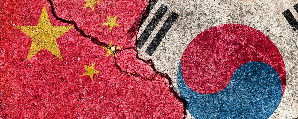 China and South Korea flags on cracked concrete 