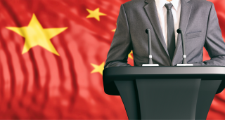Man at podium next to Chinese flag