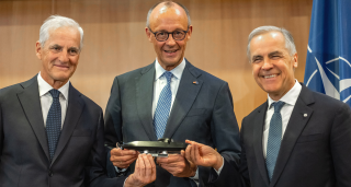 German Chancellor Friedrich Merz (C) holds a model TKMS (ThyssenKrupp Marine Systems) submarine alongside Canadian Prime Minister Mark Carney (R) and Norway's Prime Minister Jonas Gahr Store during a meeting on the sale of the German-Norway developed TKMS submarine 