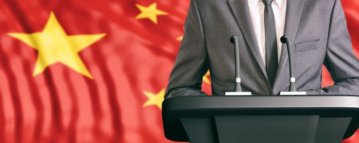 Man making speech next to Chinese flag