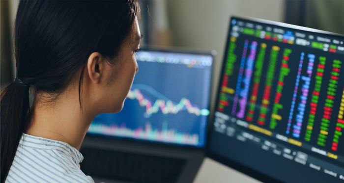 Woman gazes at trading data on computer screen