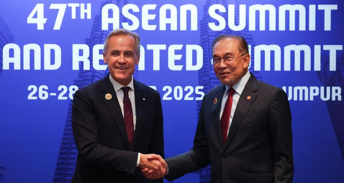 Prime Minister Mark Carney (L) shakes hands with Malaysia's Prime Minister Anwar Ibrahim
